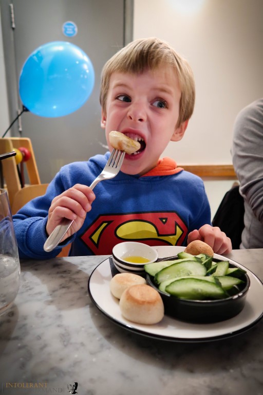 Callum celebrating his birthday at Pizza Express, with free from dough balls and cucumber sticks (gluten free, dairy free) and a blue balloon in the background