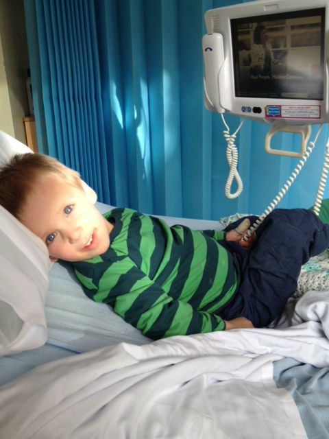Callum in hospital, requiring a nebuliser to regulate his breathing, sat on a hosital bed, looking at me, with the sun shining on him. www.intolerantgourmand.com