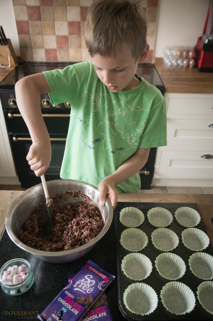 Callums chocolate crispie cakes as seen on the BBC - Callum stood in a kitchen mixing crispies, melted chocolate and melted marshmallows together, with cupcake cases in front ready to be filled. www.intolerantgourmand.com